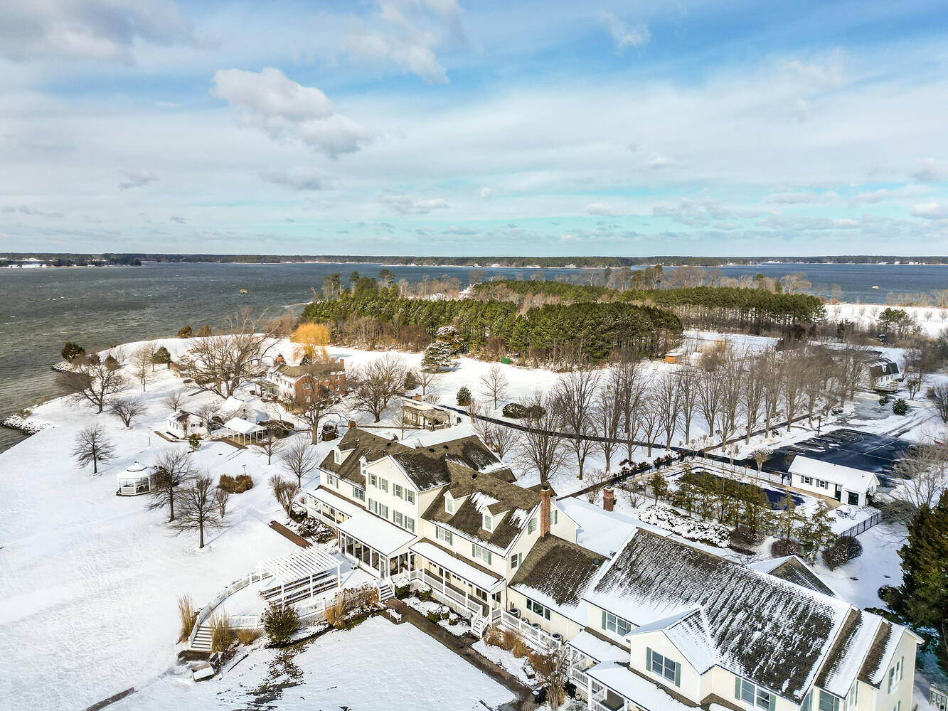 Aerial of the estate after a snow — five buildings, the bay, the trees in bare relief